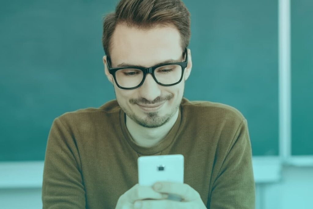 male teacher using phone in classroom
